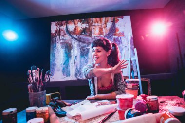 Stüdyoda iş yerinde genç sanatçı. Arka planda büyük tuval