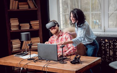 Genç adam ve kız çalış bir oyun sanal gerçeklik gözlükleri ile dolap odası. 