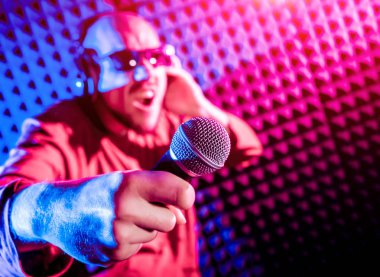 Kayıt stüdyosu olarak bir mikrofon ile şarkıcı söylüyor. Modern arka plan