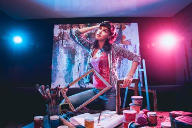 Stüdyoda iş yerinde genç sanatçı. Arka planda büyük tuval