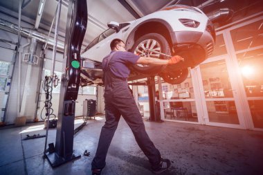 Araba mekanik teftiş yapan tekerlek ve süspansiyon ayrıntı kaldırdı otomobil servis istasyonu onarın. Oto servisi.