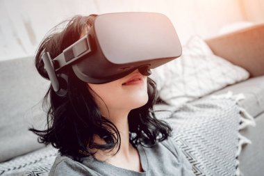 Genç kız ile sanal gerçeklik koruyucu gözlük evde oyun oynarken. VR teknolojileri