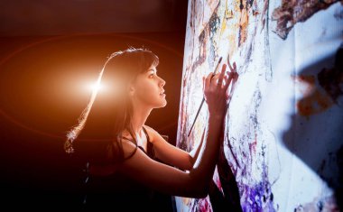 Stüdyoda iş yerinde genç sanatçı. Arka planda büyük tuval