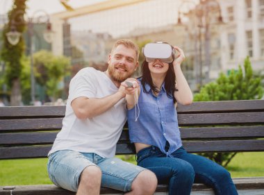 Genç çift sanal gerçeklik gözlükle sokakta bir oyun oynuyor. VR kulaklık.