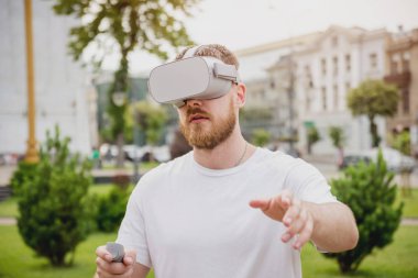 Genç Sarışın sakallı adam sokakta sanal gerçeklik gözlük takan bir oyun oynuyor. VR kulaklık.