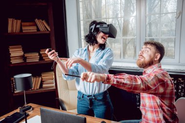 Genç adam ve kız çalış bir oyun sanal gerçeklik gözlükleri ile dolap odası. 