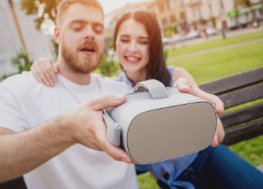 Genç çift sanal gerçeklik gözlükle sokakta bir oyun oynuyor. VR kulaklık.