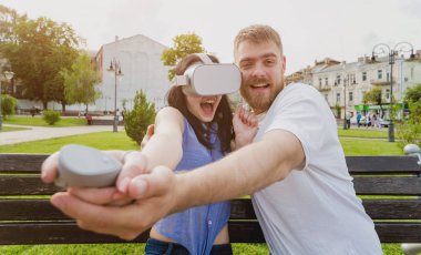 Genç çift sanal gerçeklik gözlükle sokakta bir oyun oynuyor. VR kulaklık.