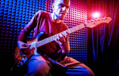Genç adam gitar ses kayıt stüdyosu içinde oynamaya. Modern arka plan