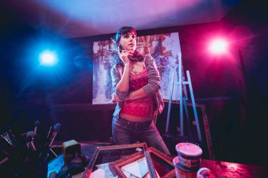 Stüdyoda iş yerinde genç sanatçı. Arka planda büyük tuval