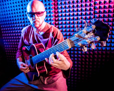 Akustik gitar ses kayıt Studio oynayan genç adam. Modern arka plan