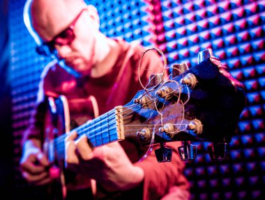 Akustik gitar ses kayıt Studio oynayan genç adam. Modern arka plan