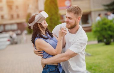 Genç çift sanal gerçeklik gözlükle sokakta bir oyun oynuyor. VR kulaklık.