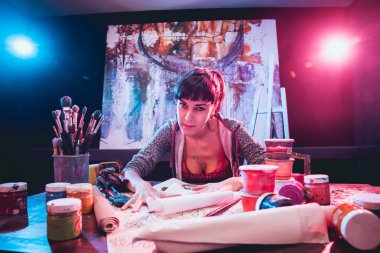 Stüdyoda iş yerinde genç sanatçı. Arka planda büyük tuval