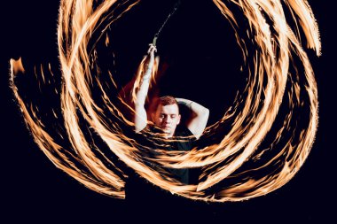 Gösteri yangın. Karanlıkta ateş performans gösteren genç adam.