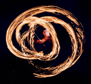 Fire show. Young man showing fire performance in darkness. clipart