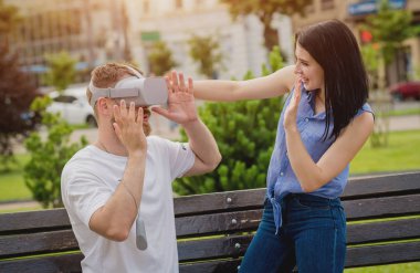 Genç çift sanal gerçeklik gözlükle sokakta bir oyun oynuyor. VR kulaklık.