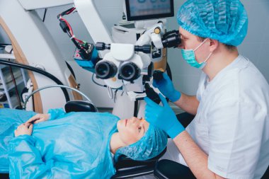 patient and surgeon in operating room during ophthalmic surgery clipart