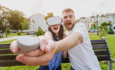 Genç çift sanal gerçeklik gözlükle sokakta bir oyun oynuyor. VR kulaklık.