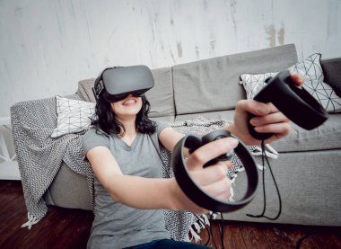 Genç kız ile sanal gerçeklik koruyucu gözlük evde oyun oynarken. VR teknolojileri
