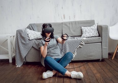 Genç kız ile sanal gerçeklik koruyucu gözlük evde oyun oynarken. VR teknolojileri