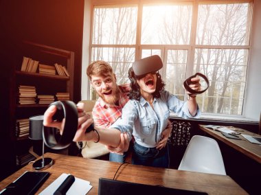 Genç adam ve kız çalış bir oyun sanal gerçeklik gözlükleri ile dolap odası. 