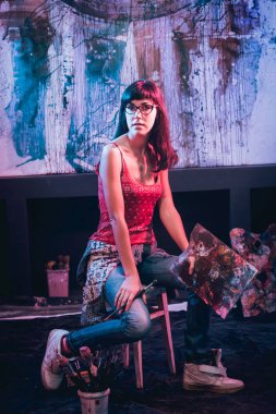 Stüdyoda iş yerinde genç sanatçı. Arka planda büyük tuval