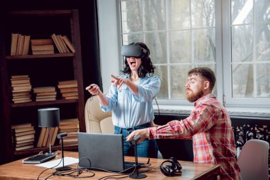Genç adam ve kız çalış bir oyun sanal gerçeklik gözlükleri ile dolap odası. 