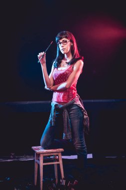 Stüdyoda iş yerinde genç sanatçı. Arka planda büyük tuval