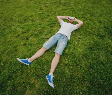 Genç sakallı adam gözlük çim üzerinde yalan sanal gerçekliğin bir oyun oynar. VR kulaklık