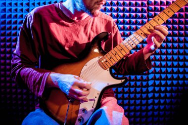 Genç adam gitar ses kayıt stüdyosu içinde oynamaya. Modern arka plan
