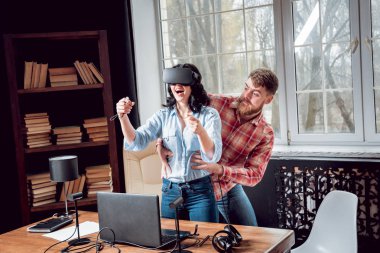 Genç adam ve kız çalış bir oyun sanal gerçeklik gözlükleri ile dolap odası. 