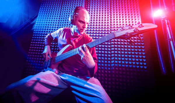 Bas gitar ses kayıt Studio oynayan genç adam. Modern arka plan