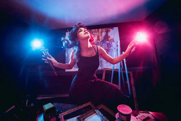 Stüdyoda iş yerinde genç sanatçı. Arka planda büyük tuval