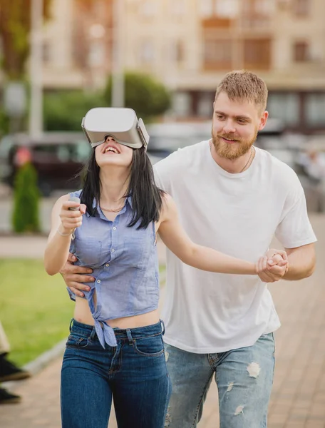 Genç çift sanal gerçeklik gözlükle sokakta bir oyun oynuyor. VR kulaklık.