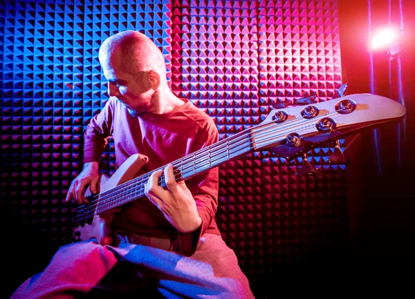 Bas gitar ses kayıt Studio oynayan genç adam. Modern arka plan