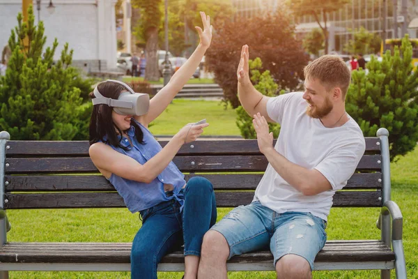 Genç çift sanal gerçeklik gözlükle sokakta bir oyun oynuyor. VR kulaklık.