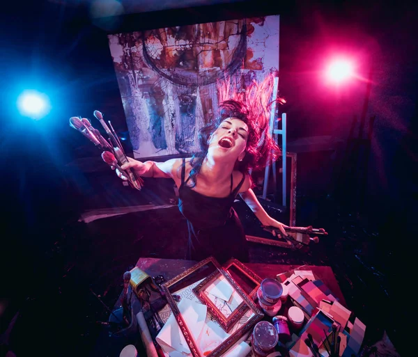 Stüdyoda iş yerinde genç sanatçı. Arka planda büyük tuval