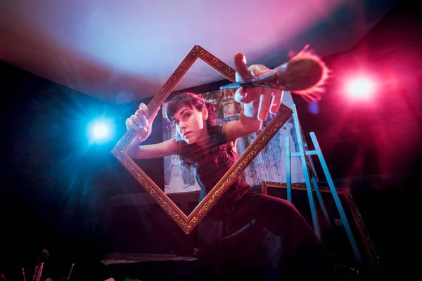 Stüdyoda iş yerinde genç sanatçı. Arka planda büyük tuval