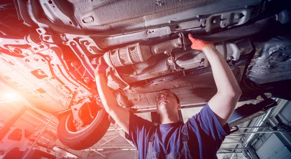 Car mechanic repair car suspension of lifted automobile at repair service station. Background