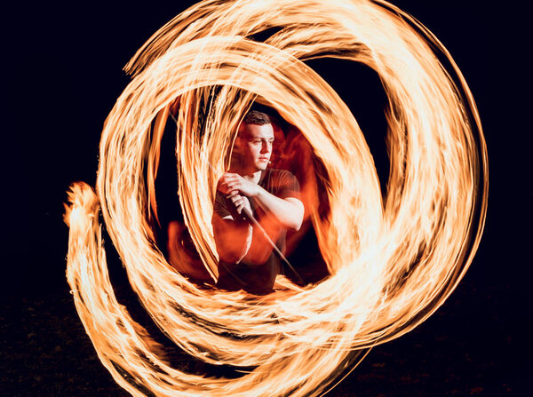 Fire show. Young man showing fire performance in darkness.