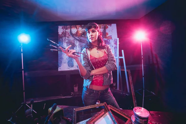 Stüdyoda iş yerinde genç sanatçı. Arka planda büyük tuval