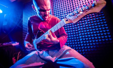 Genç adam gitar ses kayıt stüdyosu içinde oynamaya. Modern arka plan