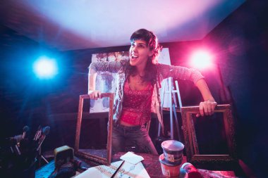 Stüdyoda iş yerinde genç sanatçı. Arka planda büyük tuval