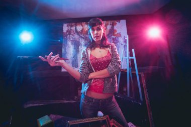 Stüdyoda iş yerinde genç sanatçı. Arka planda büyük tuval