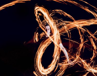 Gösteri yangın. Karanlıkta ateş performans gösteren genç adam.