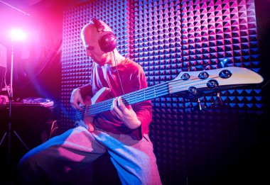 Bas gitar ses kayıt Studio oynayan genç adam. Modern arka plan
