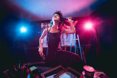 Stüdyoda iş yerinde genç sanatçı. Arka planda büyük tuval