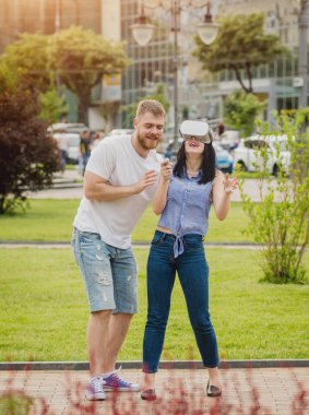 Genç çift sanal gerçeklik gözlükle sokakta bir oyun oynuyor. VR kulaklık.