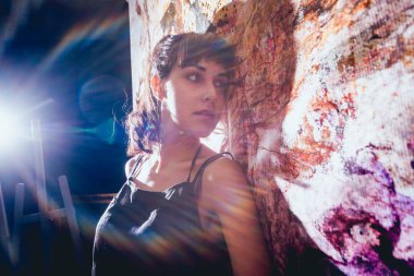 Stüdyoda iş yerinde genç sanatçı. Arka planda büyük tuval